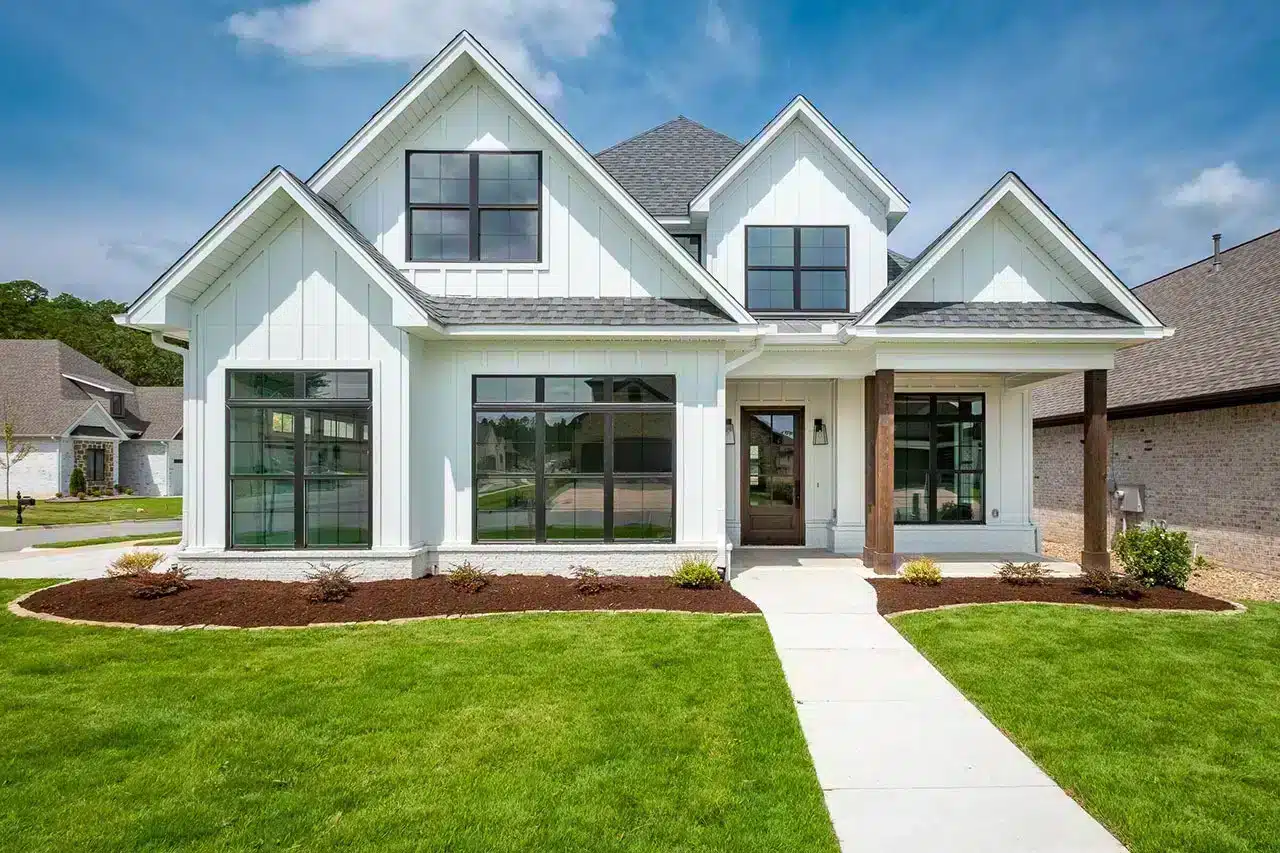 3 bedroom home plan.webp A modern two-story, 3 bedroom house plan with white siding, large windows, and a covered front entrance, surrounded by a green lawn and fresh landscaping under a blue sky—perfect for your house Plan Wishlist.