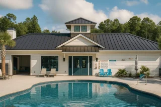 Coastal House Plans 10 Front view of a Coastal-style pool house featuring horizontal lap siding, board and batten accents, and a standing-seam metal roof surrounded by a relaxing pool deck